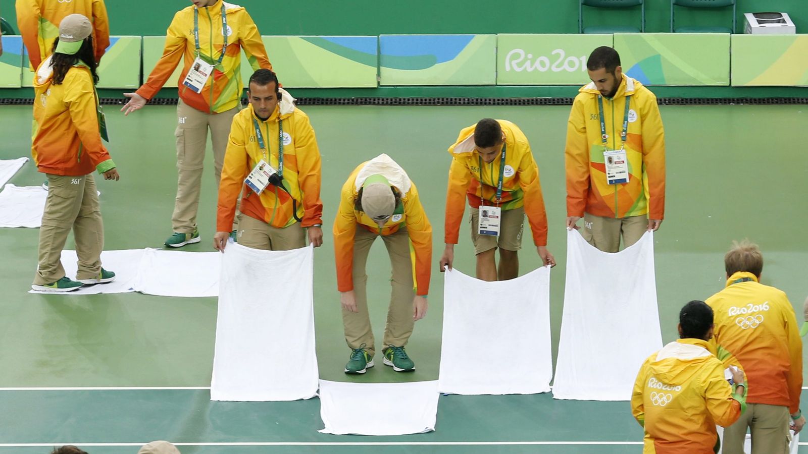 Foto: Voluntarios intentando achicar el agua de la pista de tenis de Río (Michael Reynorlds/EFE)