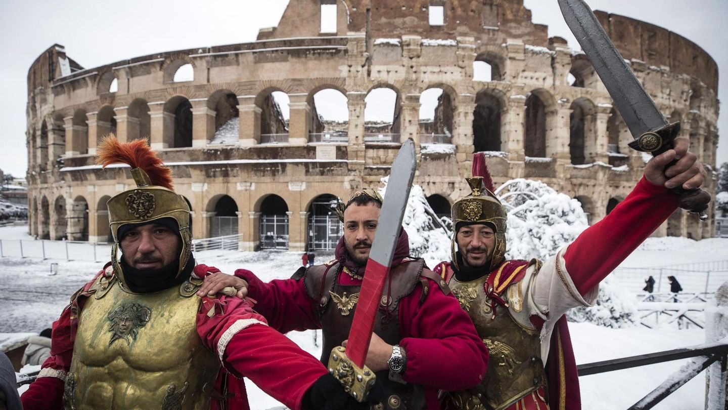 Tres hombres vestidos de centuriones romanos posan frente al Coliseo en Roma. (EFE)