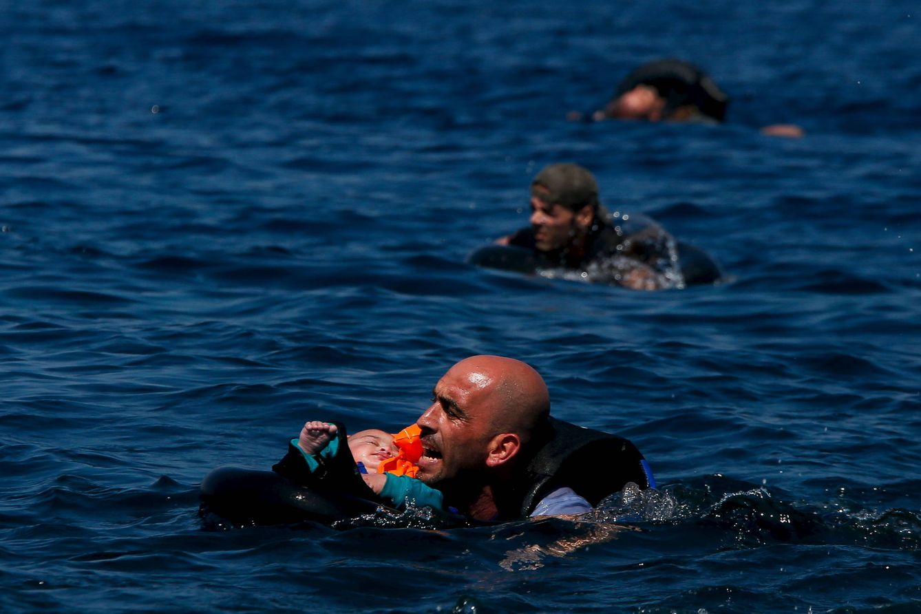 Un refugiado sirio sostiene a un bebé mientras nada hacia la costa de la isla de Lesbos, Grecia. (Reuters)