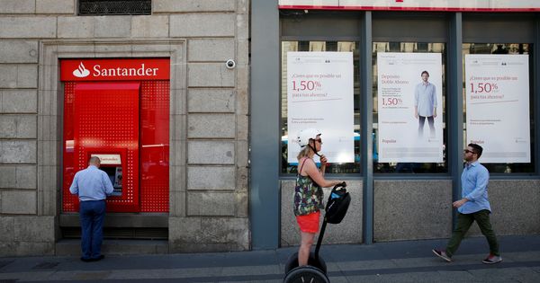 Foto: Un hombre utiliza un cajero del Santander junto a una sucursal del Banco Popular. (Reuters)