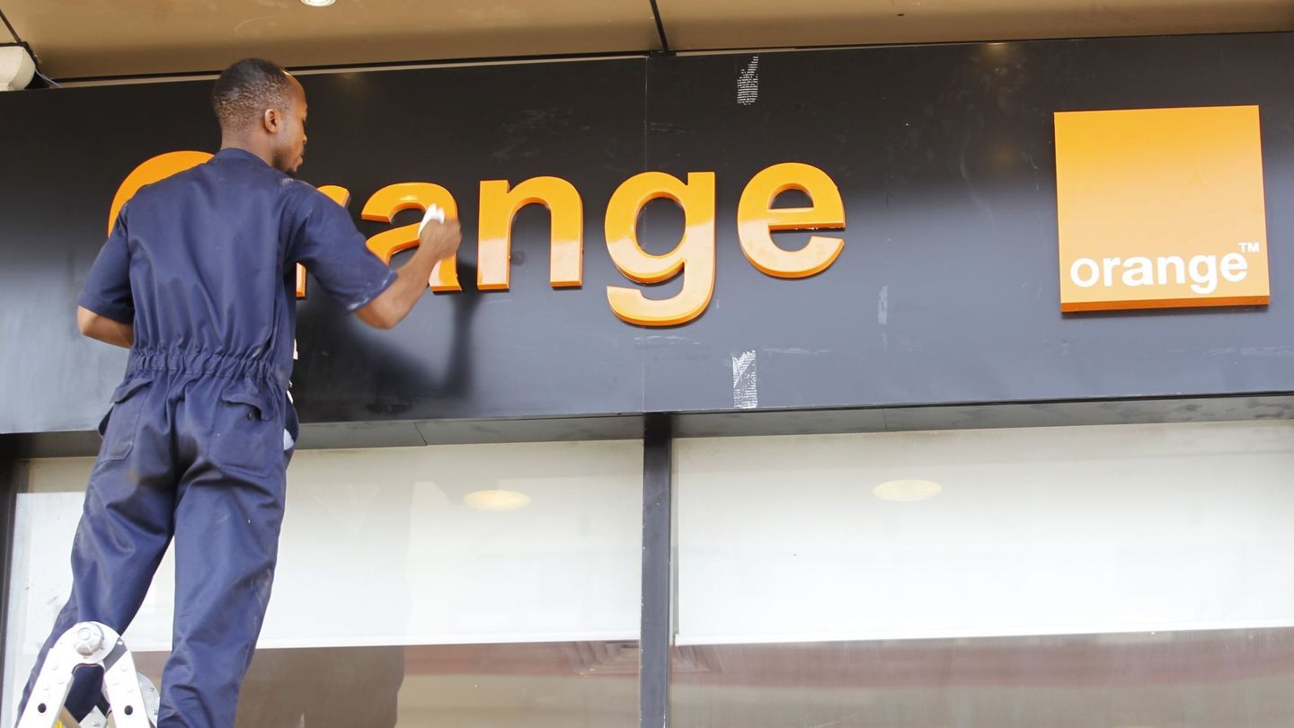 Un operario limpia un cartel de Orange. (EFE)