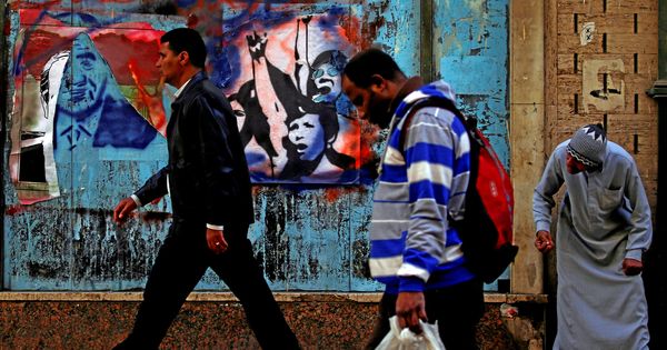 Foto: Un grupo de egipcios pasa frente a un mural con pintadas y pósteres electorales en El Cairo, el 8 de febrero de 2018. (Reuters)