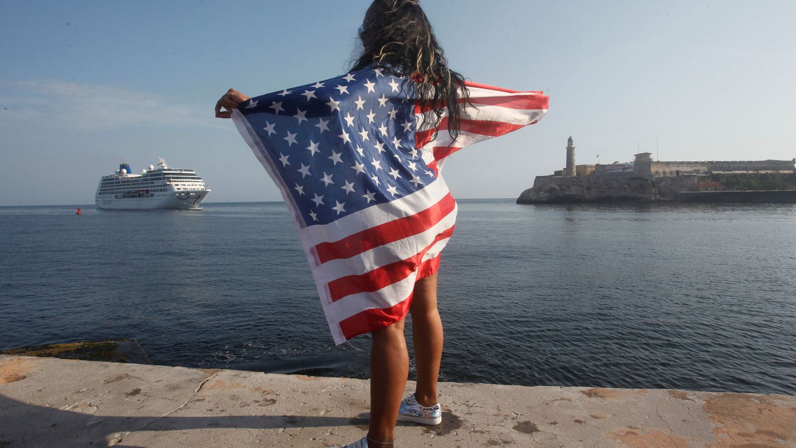 Foto: Una mujer con una bandera estadounidense aguarda la llegada del crucero 'Adonia' al puerto de La Habana, el 2 de mayo de 2016. (Reuters)