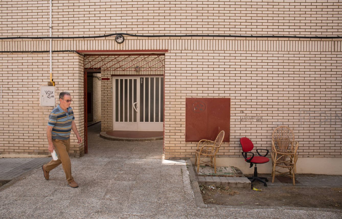 Un vecino pasa frente a la entrada de un bloque de viviendas en La Granja, Ciudad Real.