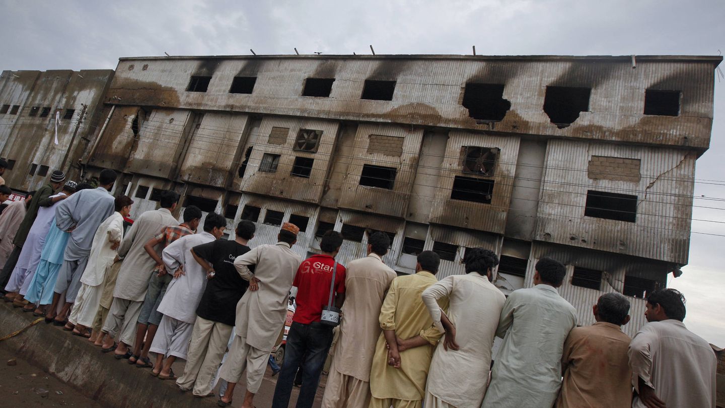 Un grupo de hombres observa la fábrica quemada, dos días después del incendio. (Reuters) 