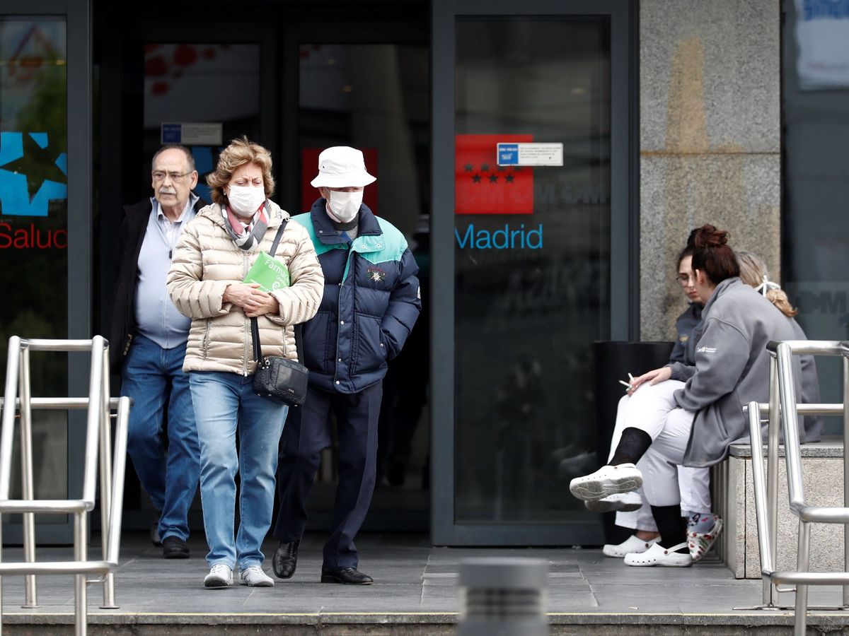 Foto: Dos personas mayores con mascarilla caminan junto a la entrada de un hospital. (EFE)