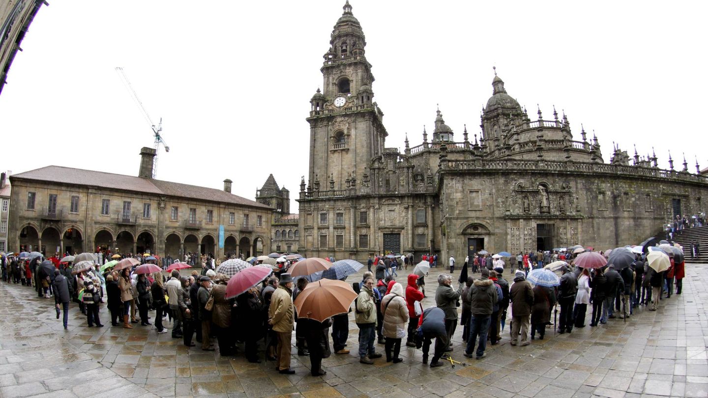 Centenares de turistas soportan fuerte lluvia para acceder a la catedral de Santiago. (EFE/Lavandeira Jr)