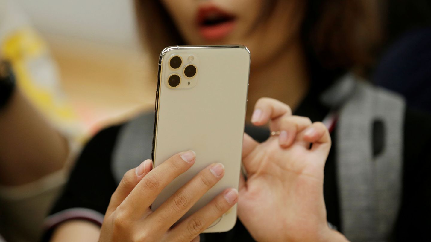 A woman holds an iPhone 11 Pro Max while giving a live broadcast after it went on sale at the Apple Store in Beijing, China, September 20, 2019. REUTERS Jason Lee