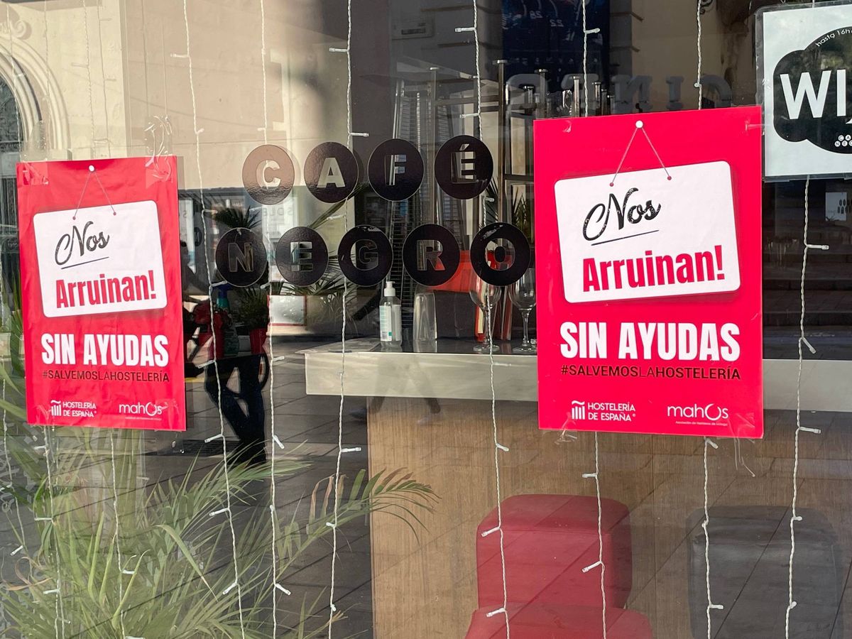 Foto: Dos carteles de la asociación de hosteleros de Málaga, reclamando ayudas, ayer, en la puerta del cerrado bar Negro. (Agustín Rivera)