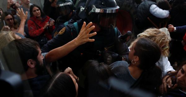 Foto: Un policía increpa a una ciudadana en el colegio donde iba a votar Carles Puigdemont. (Reuters)