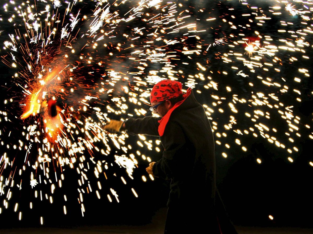 Foto: Un ciudadano baila y juega con fuego alrededor de una hoguera de San Juan instalada en el barrio de Sants de Barcelona. (EFE/Andreu Dalmau)