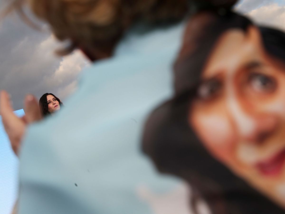 Foto: Una mujer envuelta con la cara de Ayuso. (Reuters)