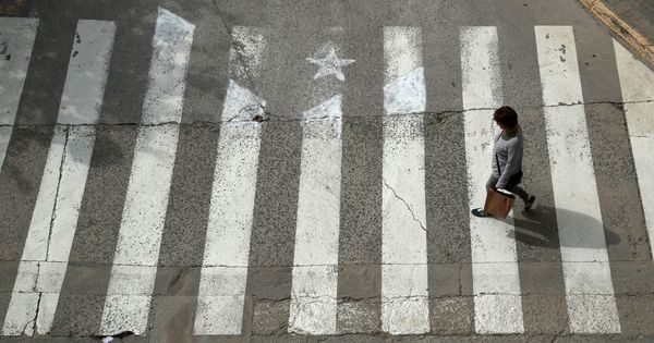Foto: Una mujer cruza por un paso de peatones pintado como una estelada. (Reuters)