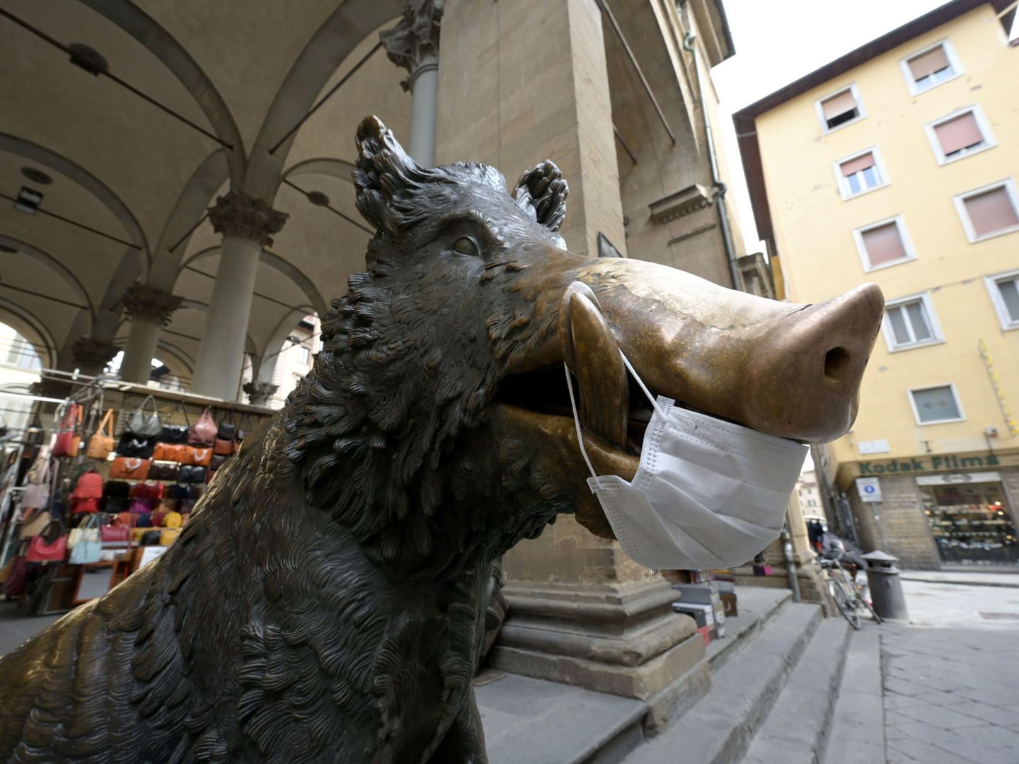 Vista del jabalí de bronce, Porcellino, con una mascarilla, en el centro de Florencia, Italia. (EFE)