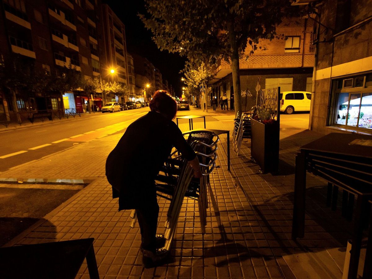 Foto: La dueña de un bar recoge la terraza minutos antes de las 22.00 hoy sábado en Aranda de Duero. (EFE)