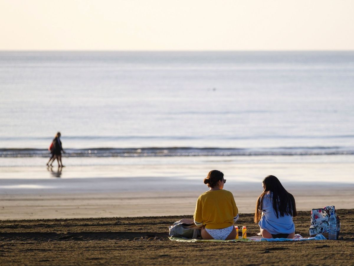 Foto: Dos jóvenes charlan en la playa de Maspalomas, en el sur de Gran Canaria. (EFE)