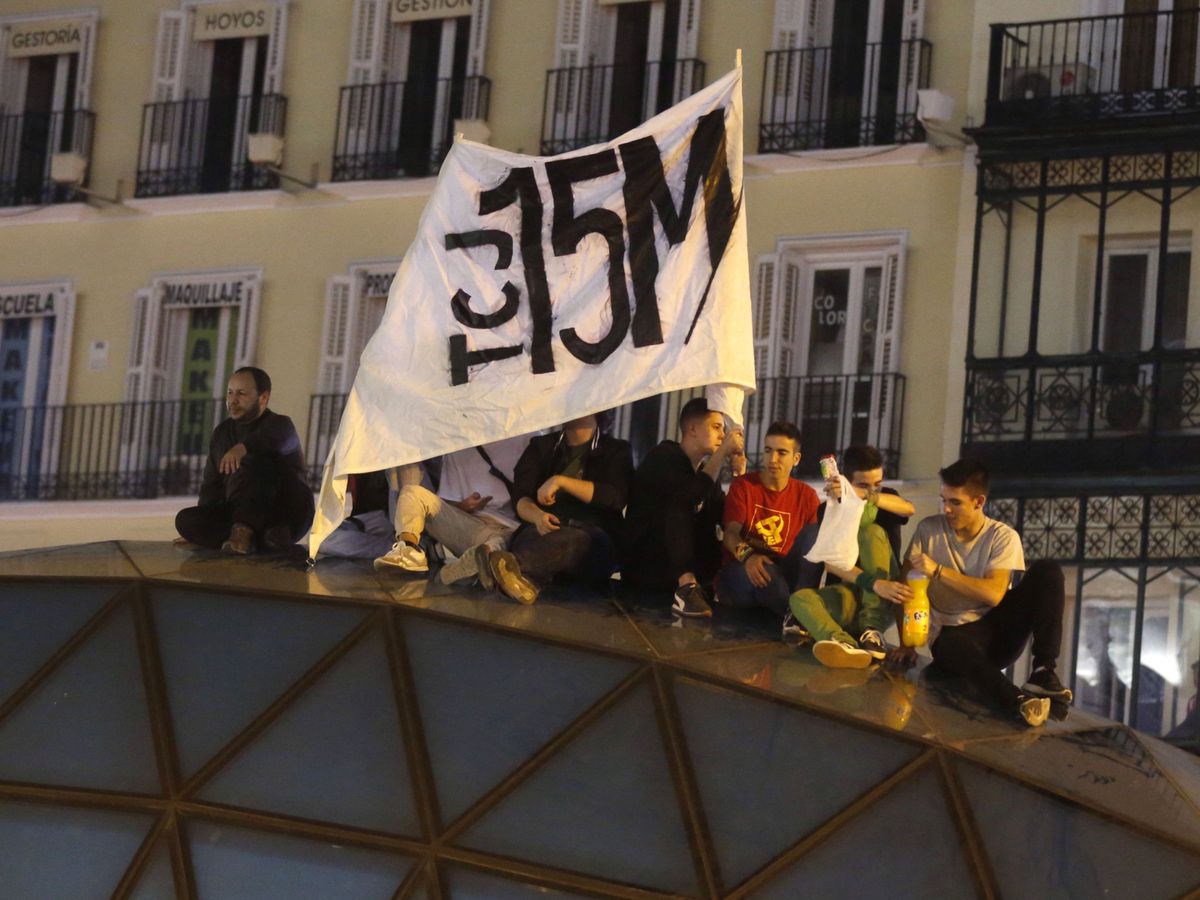 Foto: Manifestantes con una pancarta del 15-M en la Puerta del Sol de Madrid. (EFE)