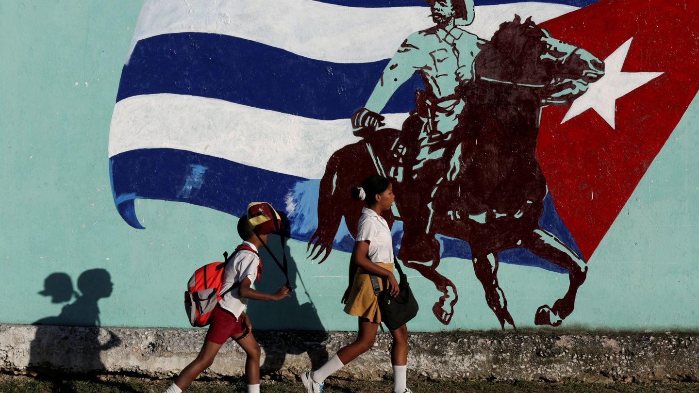 Estudiantes cubanos pasan delante de un mural en La Habana, el 22 de noviembre de 2016 (Reuters)