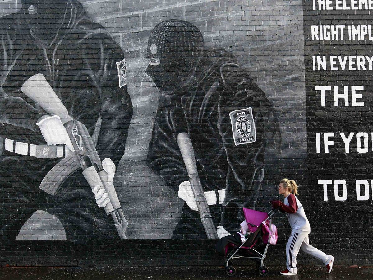 Foto: Una mujer camina frente a un mural de apoyo a los paramilitares unionistas en Belfast. (Foto: Reuters)