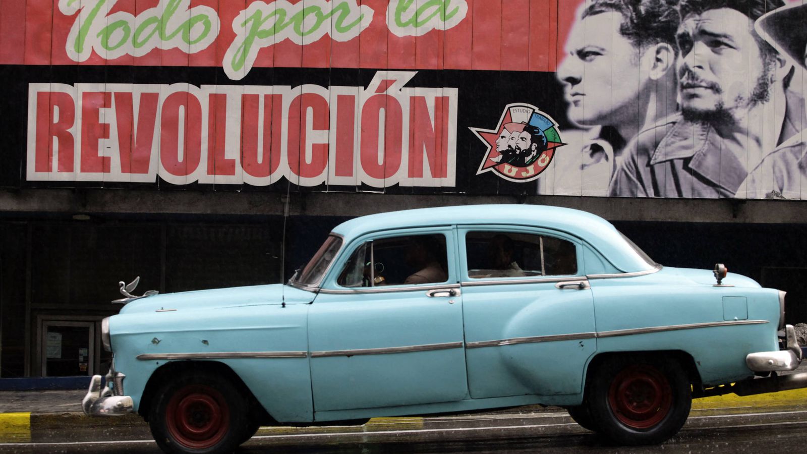 Foto: Un "almendrón", uno de los coches fabricados antes de la Revolución, pasa por delante de un cartel revolucionario en La Habana. (Reuters)