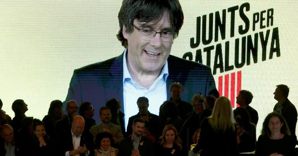 Foto: El expresidente catalán Carles Puigdemont (en la pantalla, por videoconferencia desde Bruselas) interviene en un acto de de campaña de JxCAT en Barcelona. (EFE)