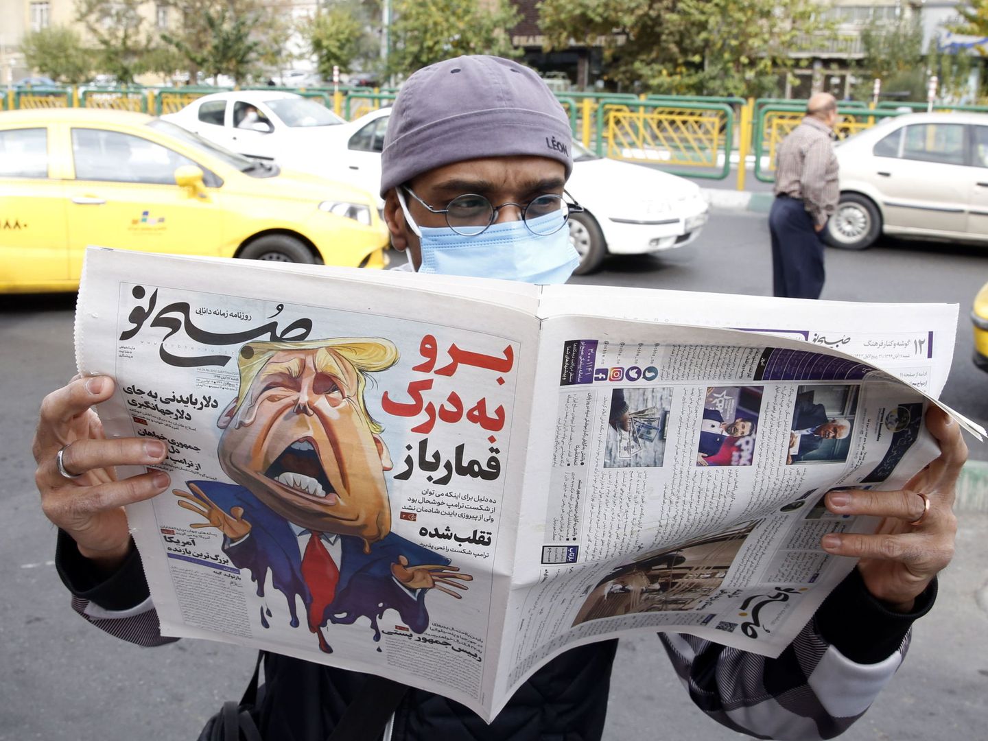 Un hombre lee la portada del periódico iraní 'Sobhe Nou', con una caricatura de Trump. (EFE)