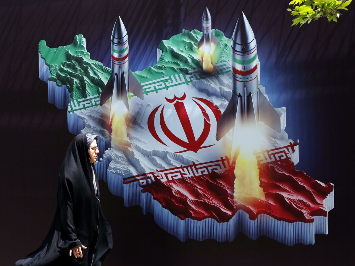Foto: Una mujer iraní pasa junto a una pancarta antiisraelí con imágenes de misiles iraníes. (EFE/Abedin Taherkenareh)