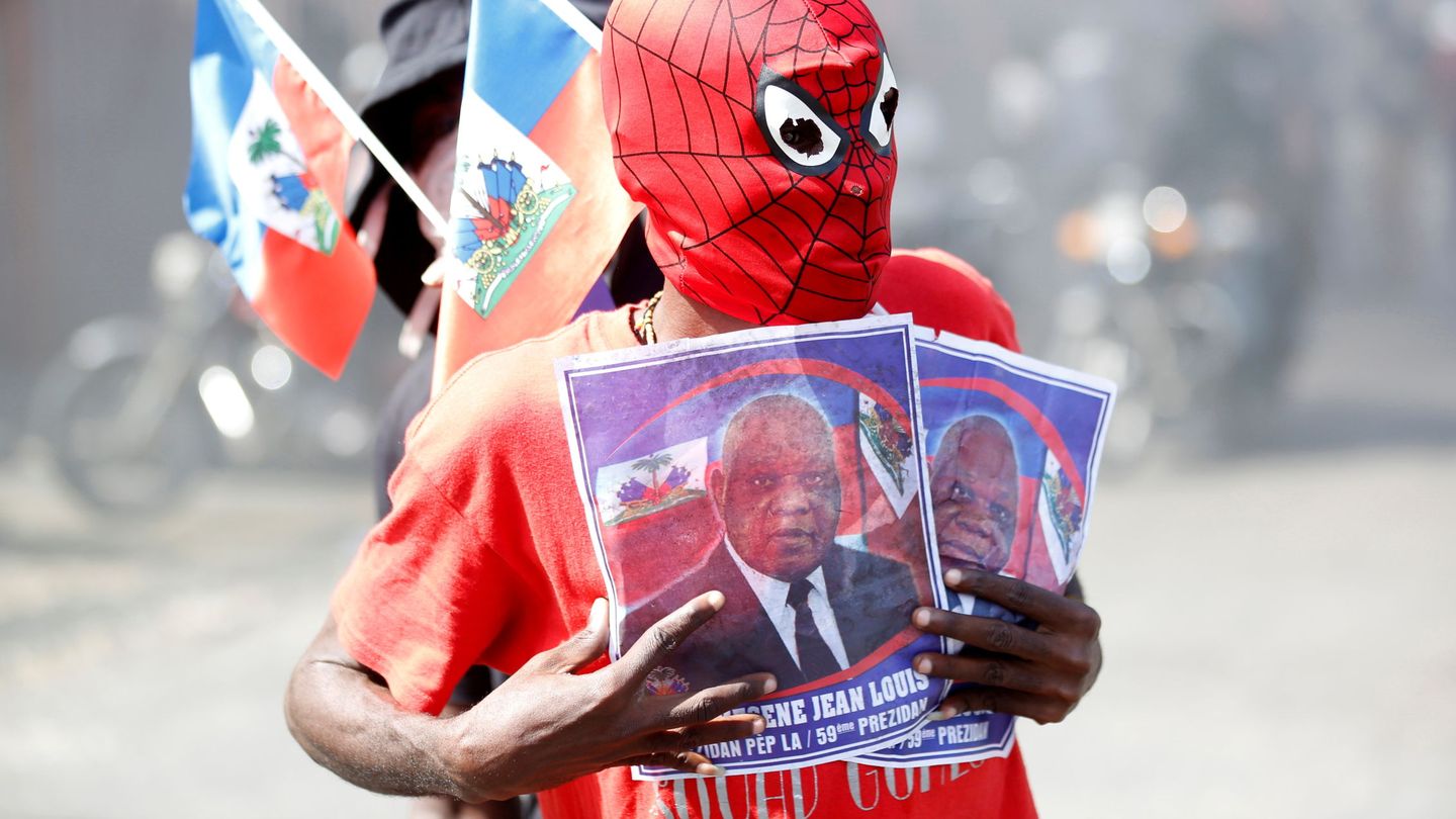 A demonstrator wearing a Spiderman mask holds photos of Supreme Court Judge Joseph Mecene Jean-Louis, as he takes part in a protest against Haiti's President Jovenel Moise, in Port-au-Prince, Haiti February 14, 2021. REUTERS Jeanty Junior August
