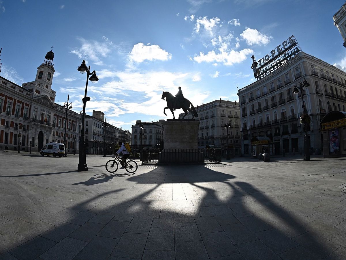 Foto: Un repartidor cruza en bicicleta la Puerta del Sol, en Madrid. (EFE)