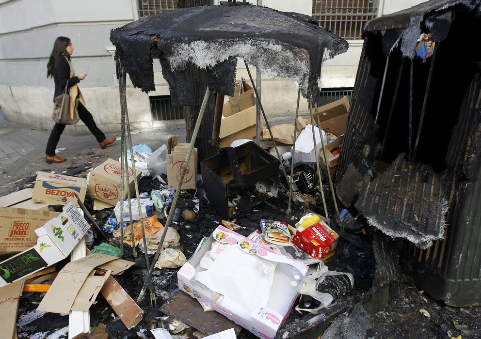 Foto:  Una mujer   pasa junto a unos contenedores quemados (Efe)