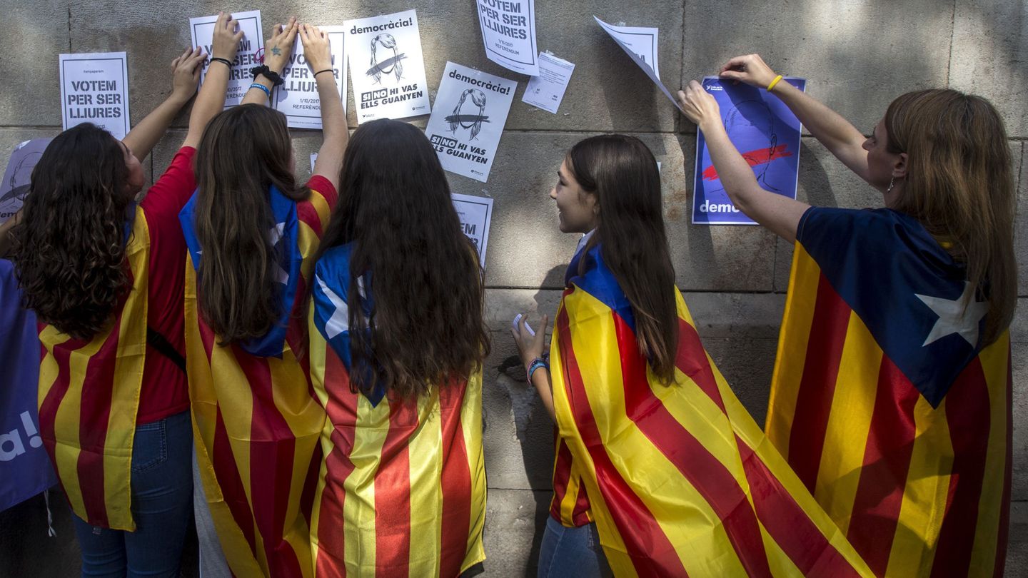 Varias estudiantes enganchan carteles en la pared de la Universidad de Barcelona. (EFE)
