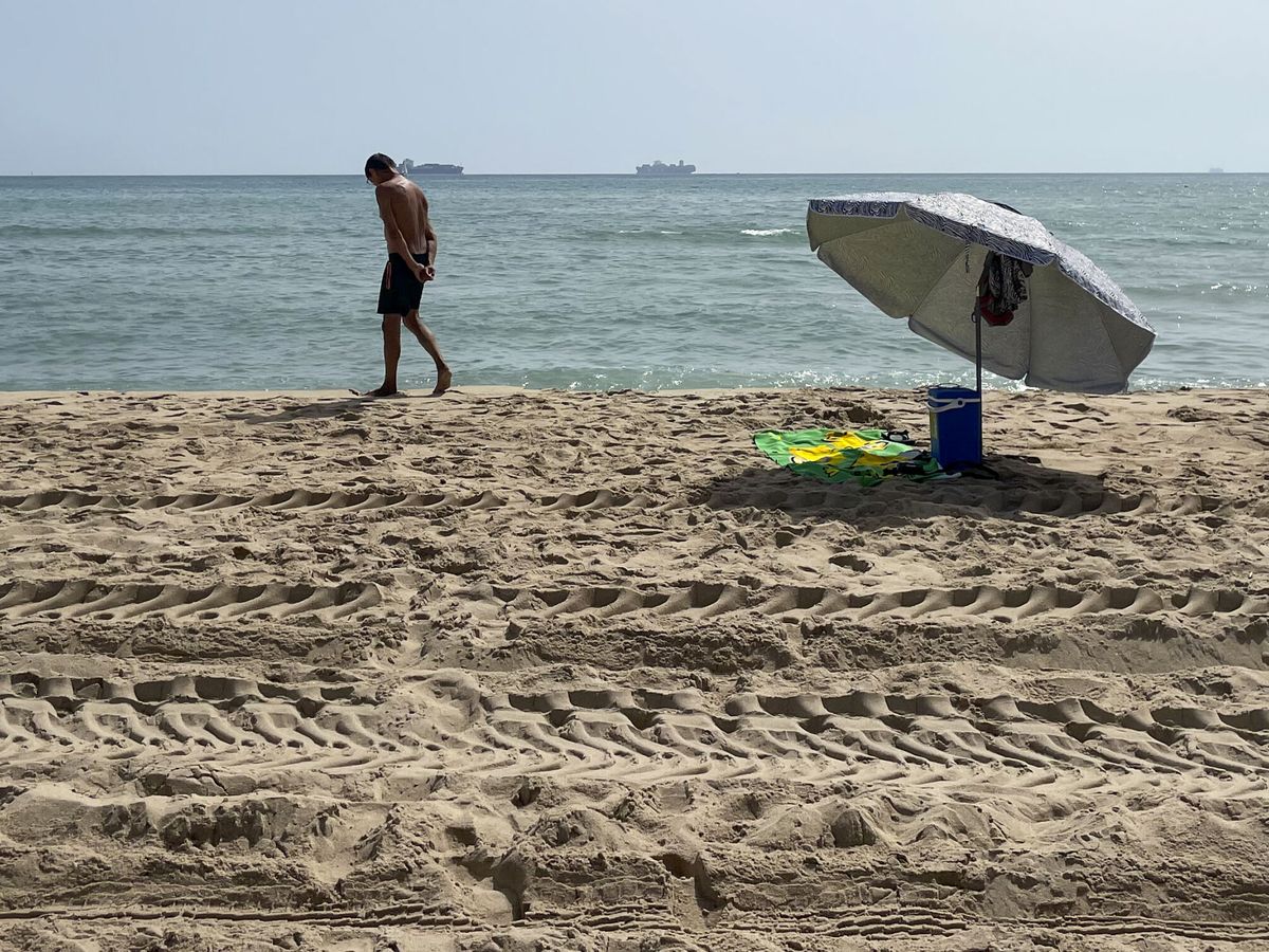 Foto: Una persona pasea por una de las tres playas del sur de Valencia afectadas desde el martes por un vertido de hidrocarburos, que han reabierto este jueves. (EFE/Raquel Segura)
