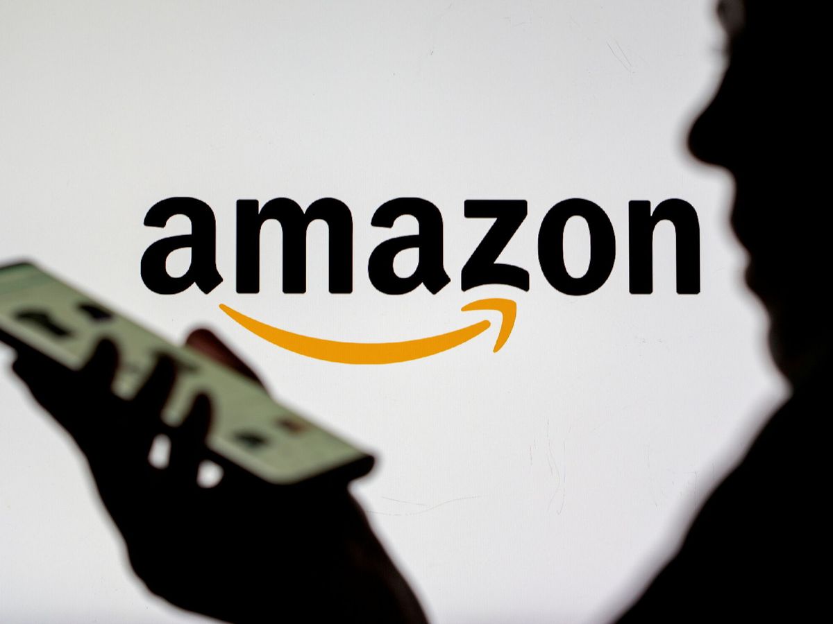 Foto: Una mujer con un 'smartphone' frente al logo de Amazon (Reuters/Ruvic)