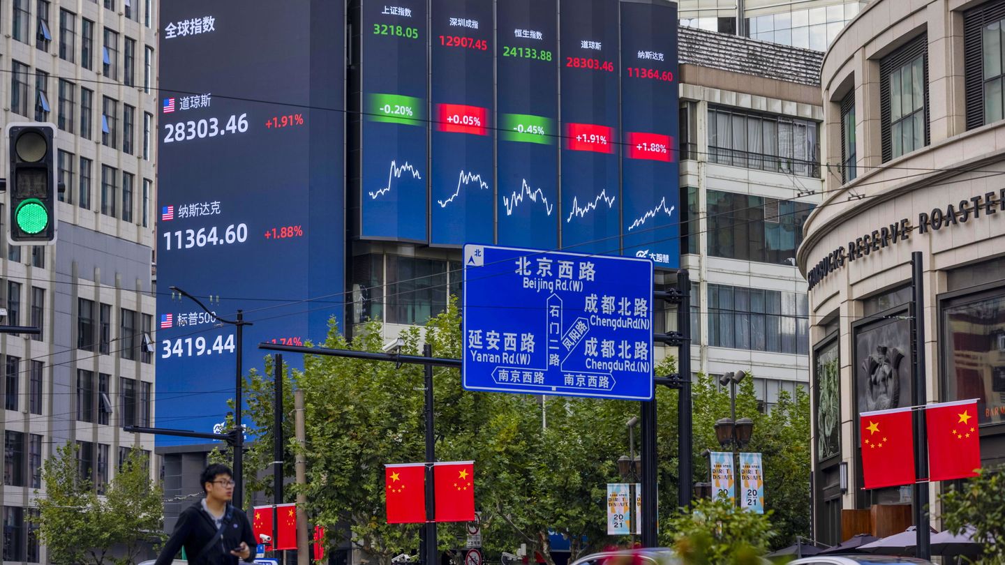 Ciudadanos pasean frente a una pantalla que muestra los índices de bolsa mundiales en Shanghái. (EFE)
