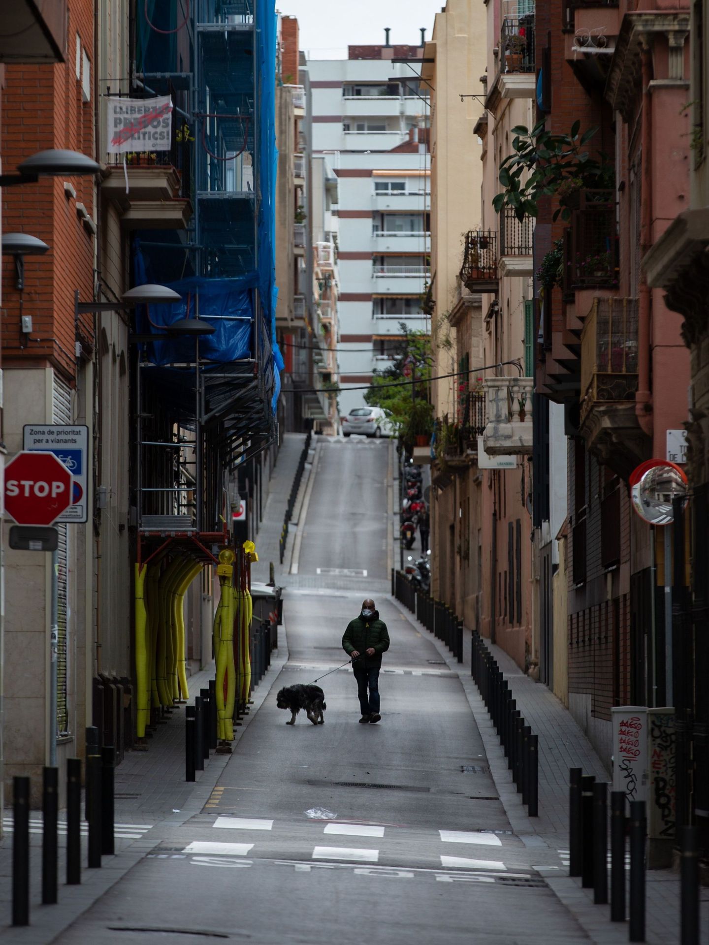 Un joven pasea su perro por una calle del barrio de Gracia, en Barcelona. (Enric Fontcuberta)
