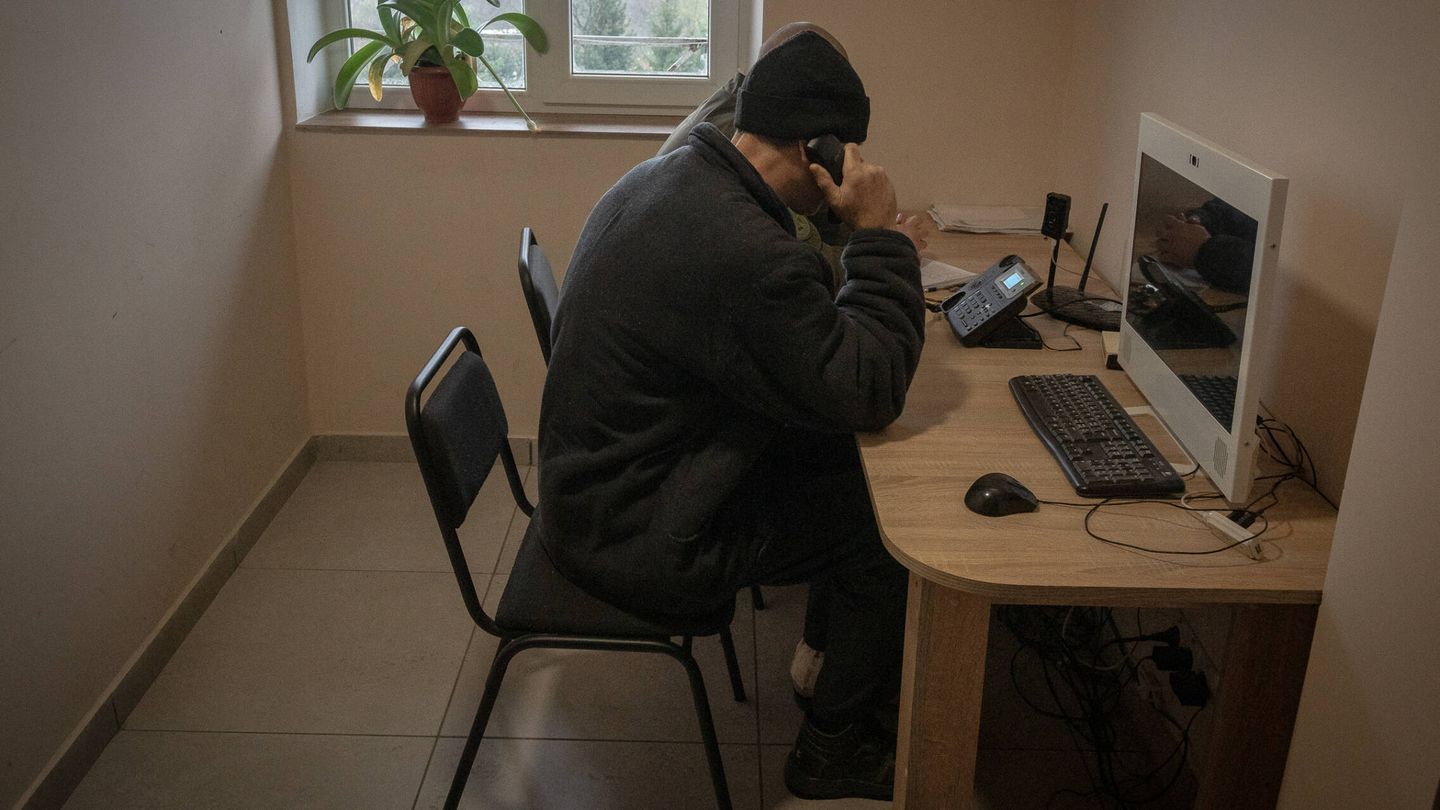 Un prisionero de guerra ruso llama a su familia, mientras un soldado ucraniano escucha atentamente la conversación. (Albert Lores)