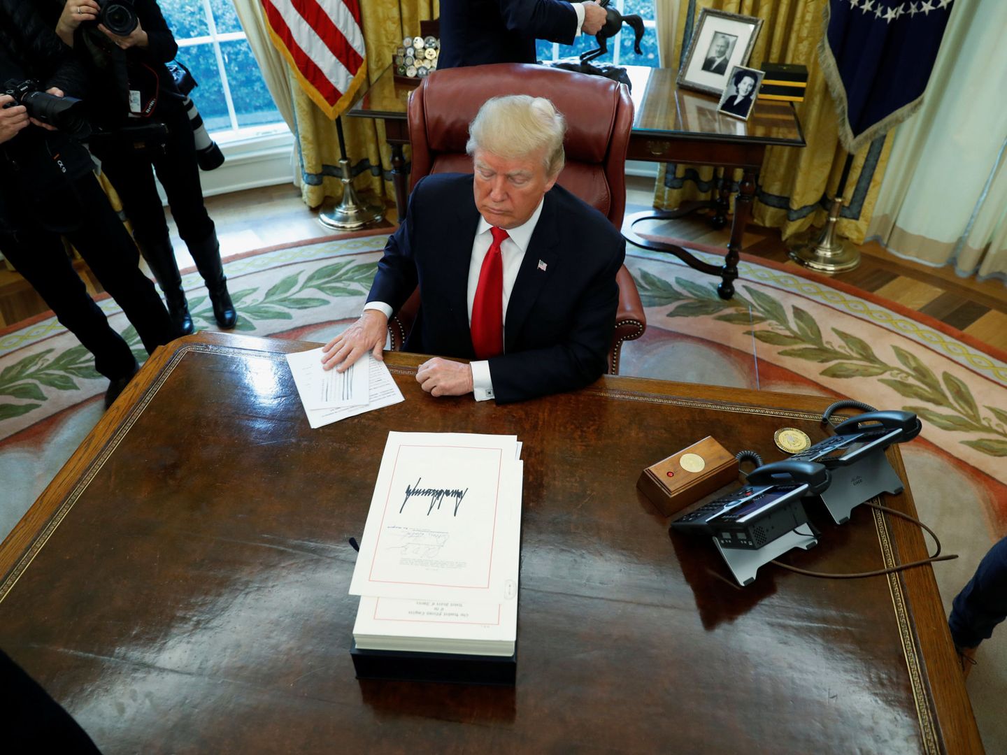 El presidente estadounidense Donald firma una ley ante la prensa en el Despacho Oval, el 22 de diciembre de 2017. (Reuters)