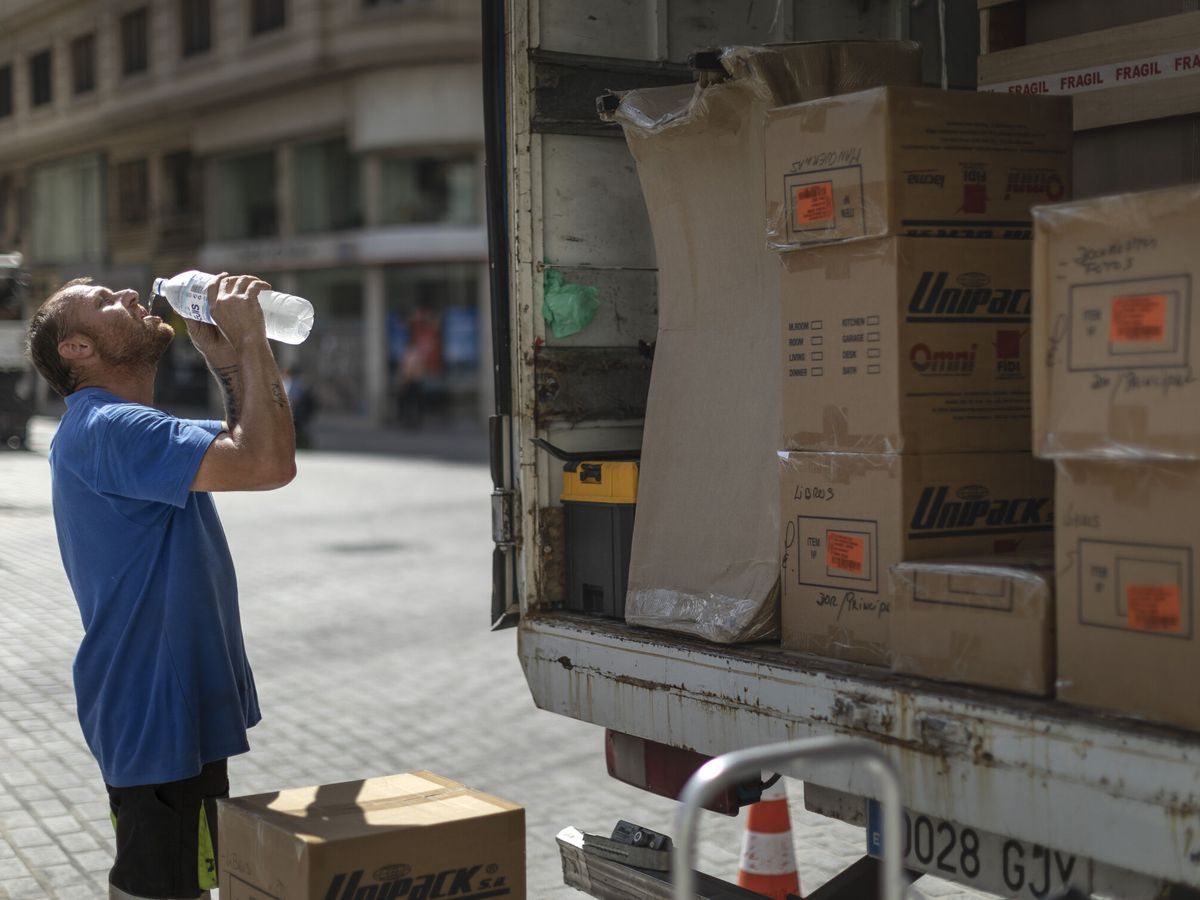Foto: Un trabajador de una empresa de mudanzas bebe agua. (EFE/ Biel Aliño)