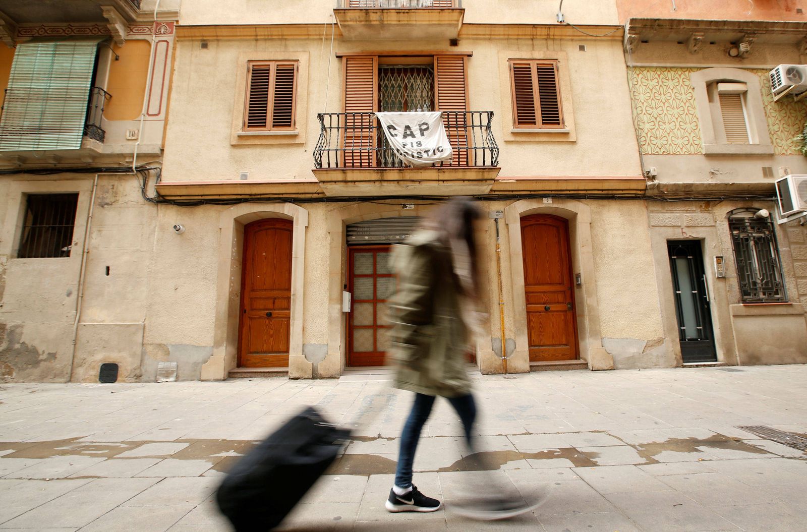 Foto: Una joven sostiene su maleta frente a una pancarta contra Airbnb. (Reuters)