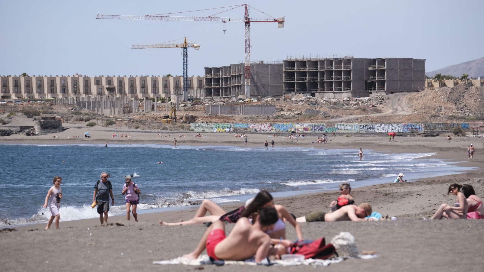 Turistas disfrutan del mar y el sol frente a las obras de construcción del hotel de La Tejita. (EFE)