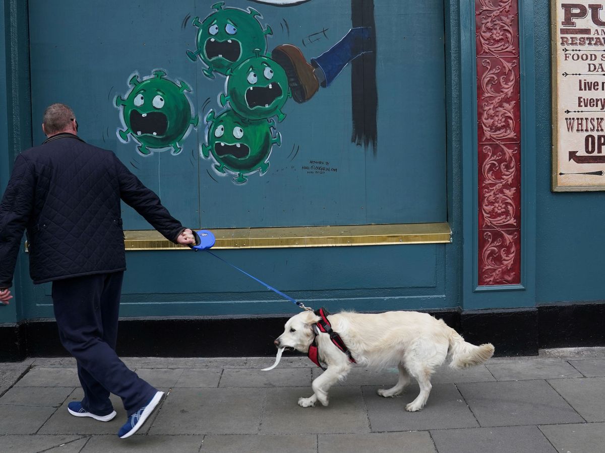 Foto: Un hombre frente a un bar en Dublin con un dibujo contra el covid. (Reuters)