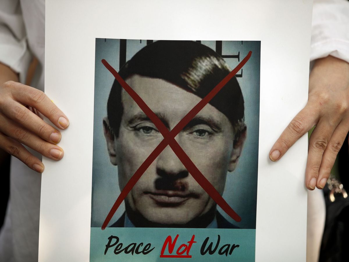 Foto: Pancarta de una protesta en contra de la guerra, donde se compara a Putin con Hitler. (EFE/Rungroj Yongrit)