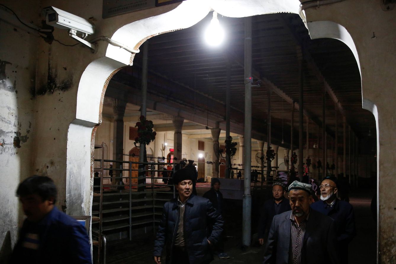 Hombres uigures pasan ante cámaras de vigilancia tras rezar en una mezquita de Hotan, en la provincia de Xinjiang. (Reuters) 
