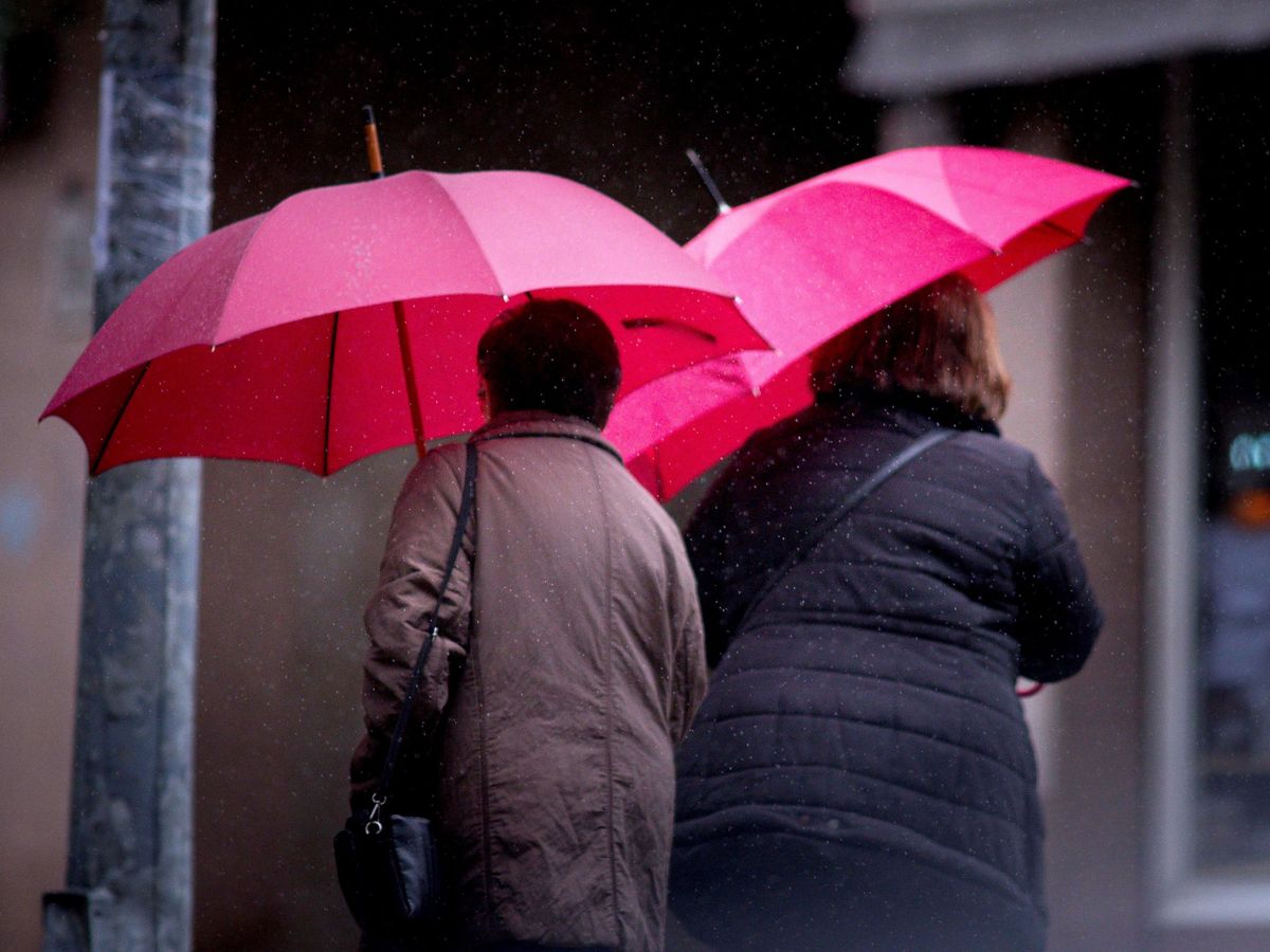 Foto: Dos mujeres ser protegen de la lluvia en las calles de Ourense. (EFE)