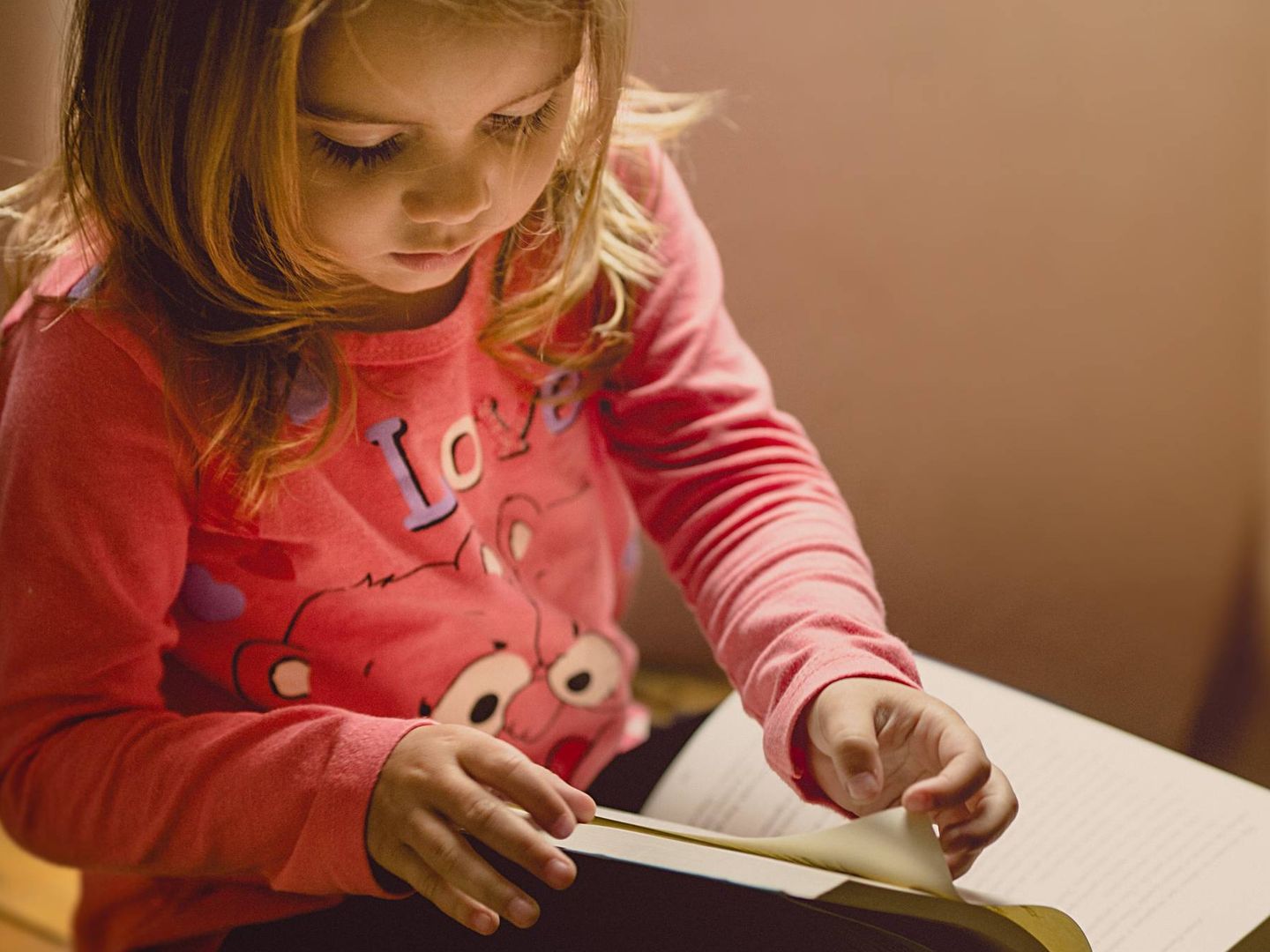 Una niña jugando con un libro. (Jonathan Borba para Unsplash)