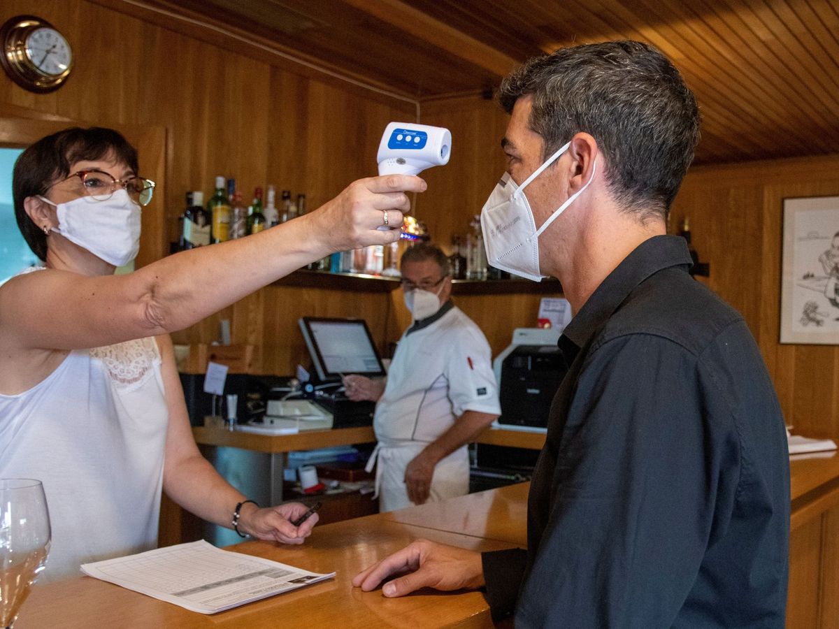 Foto: Trabajadores de un restaurante toman la temperatura a un cliente. (EFE)