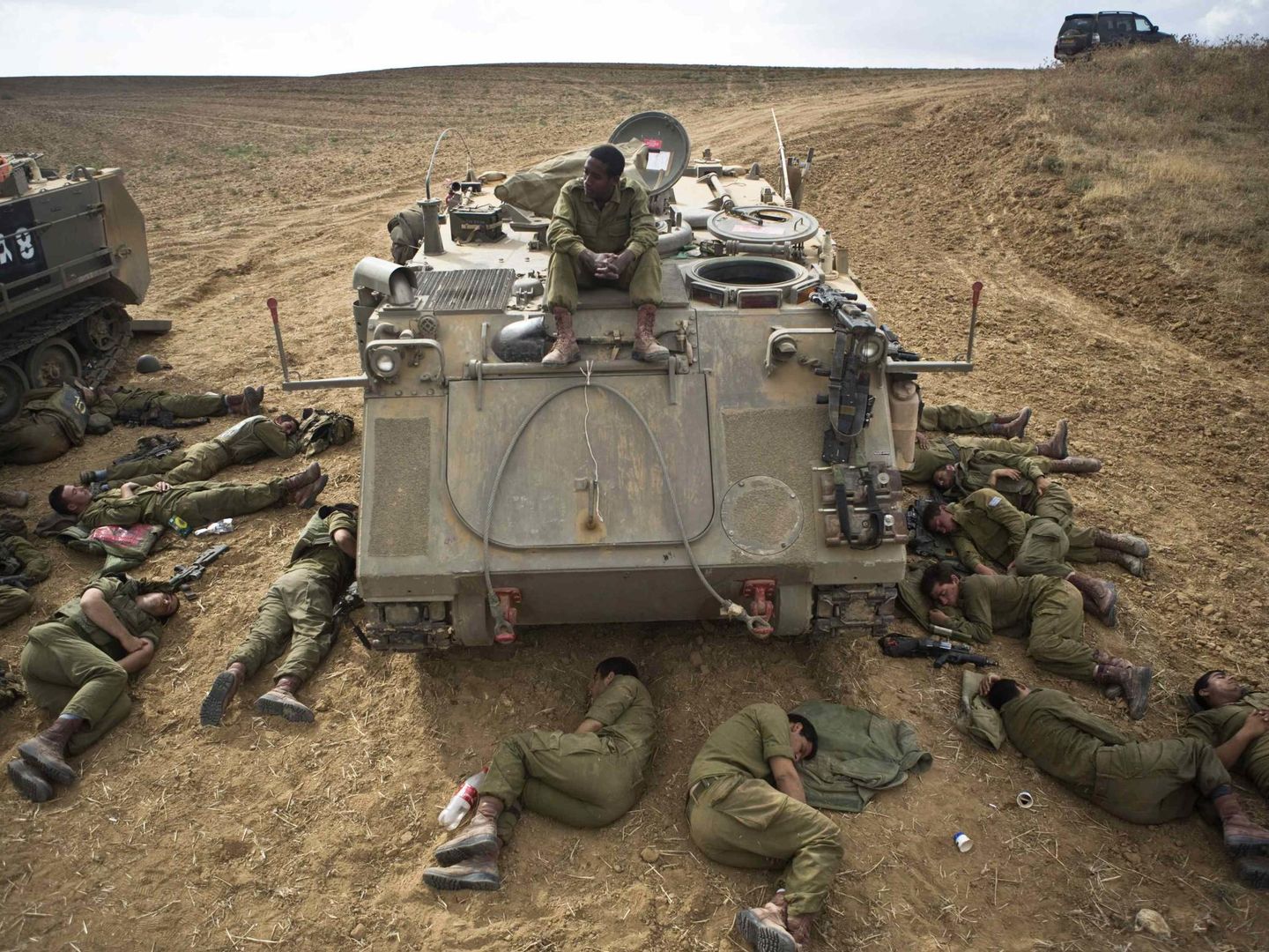 Soldados del Ejército israelí duermen en torno a un carro blindado en la frontera con la Franja de Gaza (Reuters).