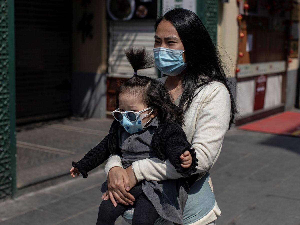 Foto: Una mujer y un bebé, con mascarillas, pasean por la calle comercial Qianmen de Pekín. (EFE)