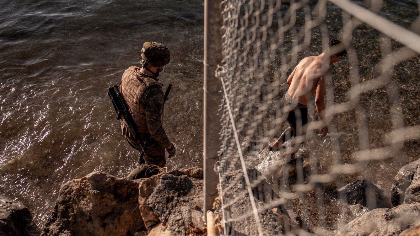 Foto: Un soldado del ejército ayuda a un inmigrante a su llegada a la playa de El Tarajal en Ceuta. (EFE)