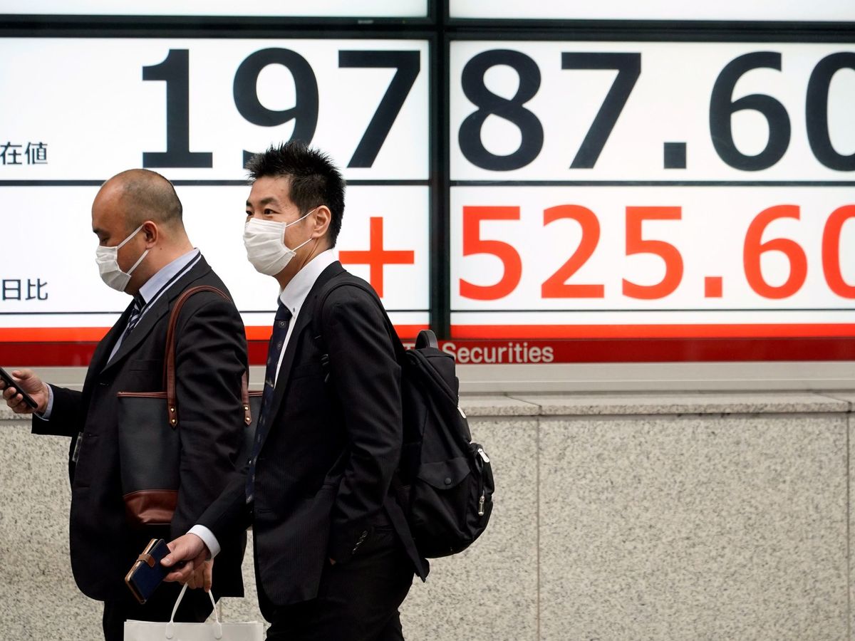 Foto: Dos personas con mascarillas protectoras caminan junto a un cartel que indica los movimientos de la Bolsa de Tokio. (EFE)